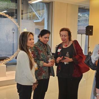 Three female doctors facing each other while standing at a reception