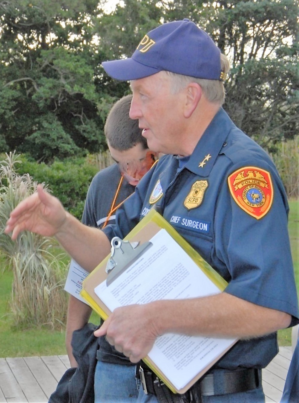 Scott Coyne in a police uniform holding a clipboard with paper